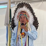 Chief Bobby Cameron standing with a microphone at a community event in Star Blanket Cree Nation.