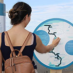 Une jeune femme explore le site de Putep't-awt à l'aide des panneaux interactifs sur l'histoire de la Première Nation Wolastoqiyik Wahsipekuk.