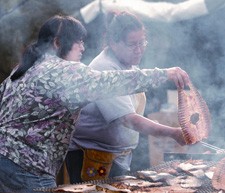 2 women preparing food on a table outside