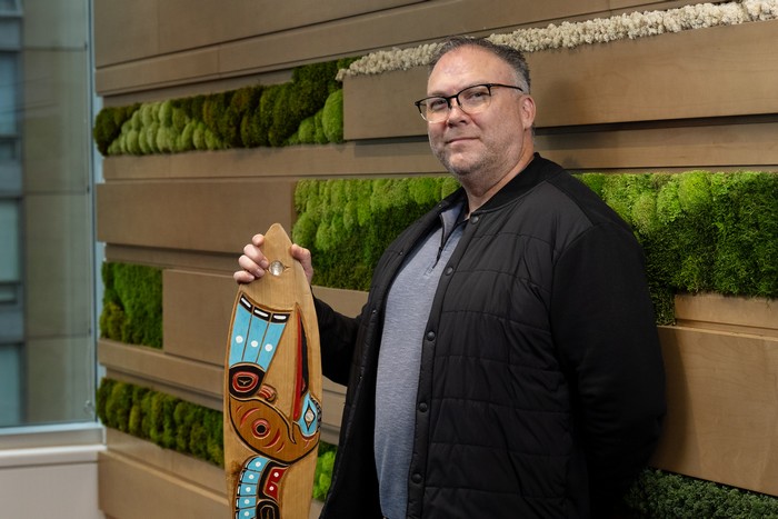 Eric Mancewich tenant une œuvre d'art autochtone en bois