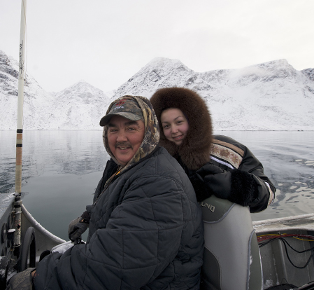 Individuals in a boat with mountains and water in the background